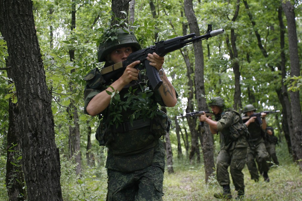 Three men in camouflage holding guns.